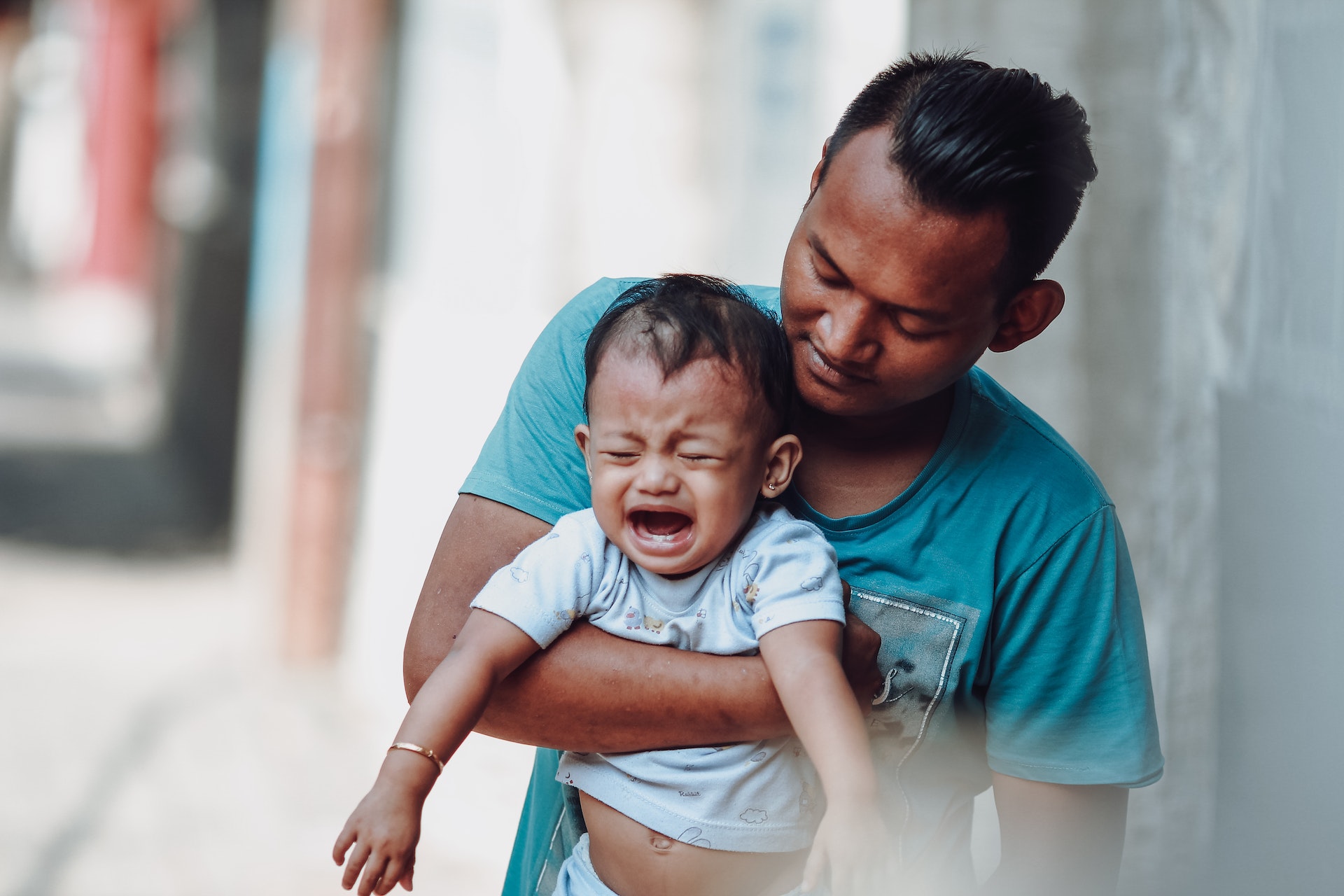 A man holding a crying child with tooth pain