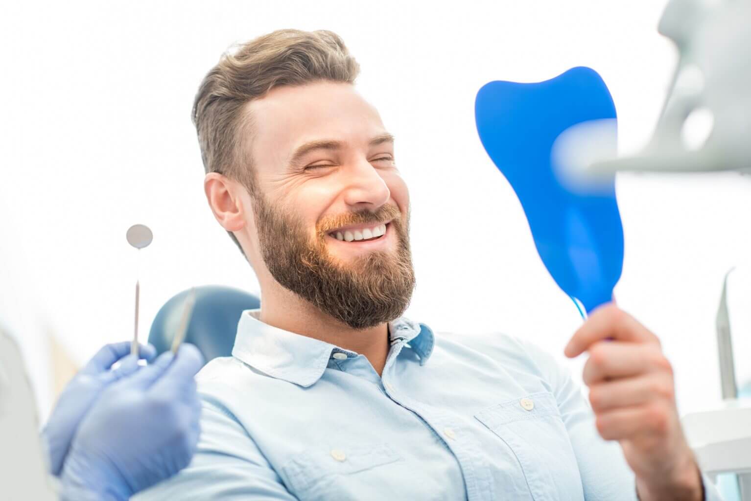 man smiling in a mirror at the dentist