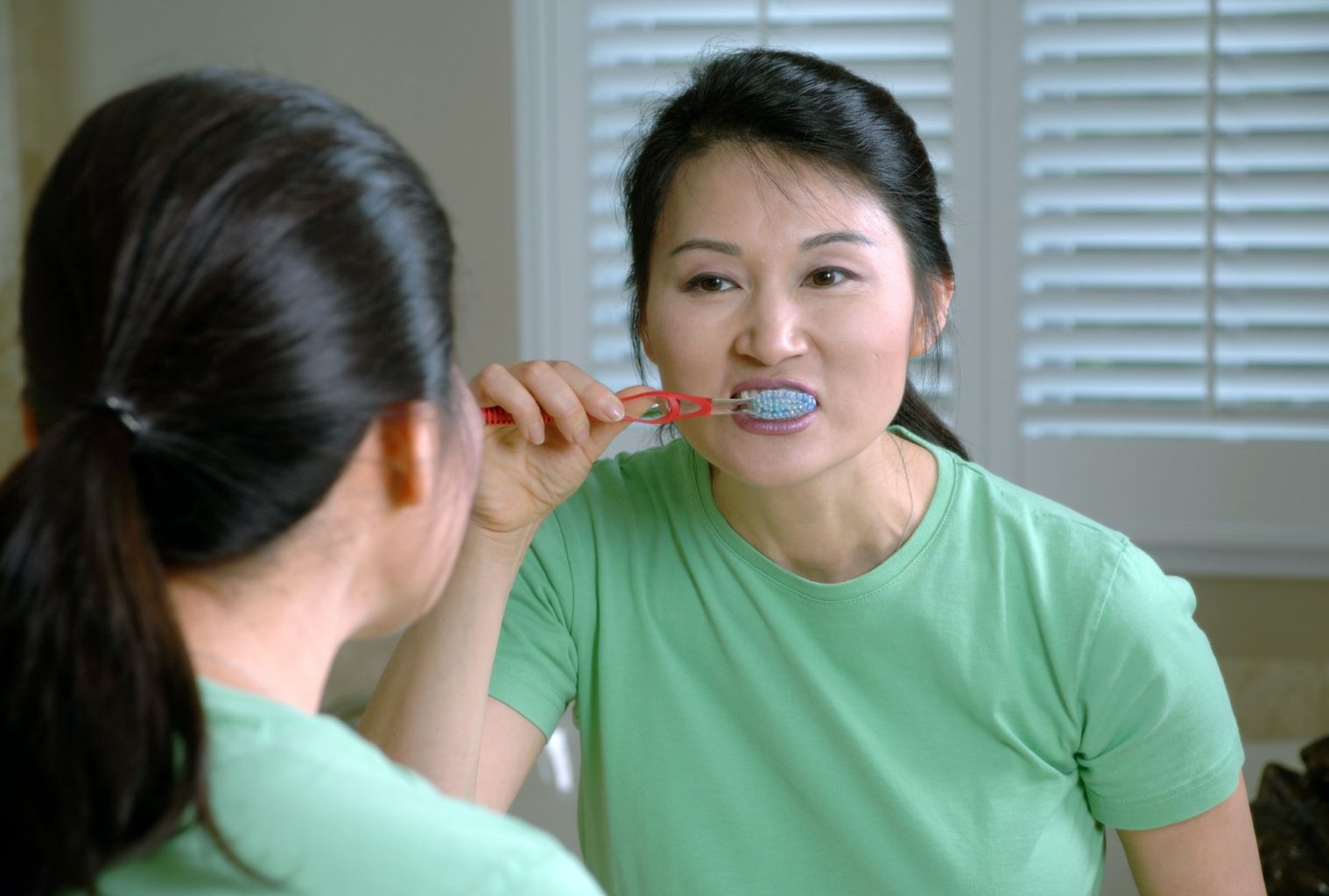 A woman brushing her teeth in the mirror