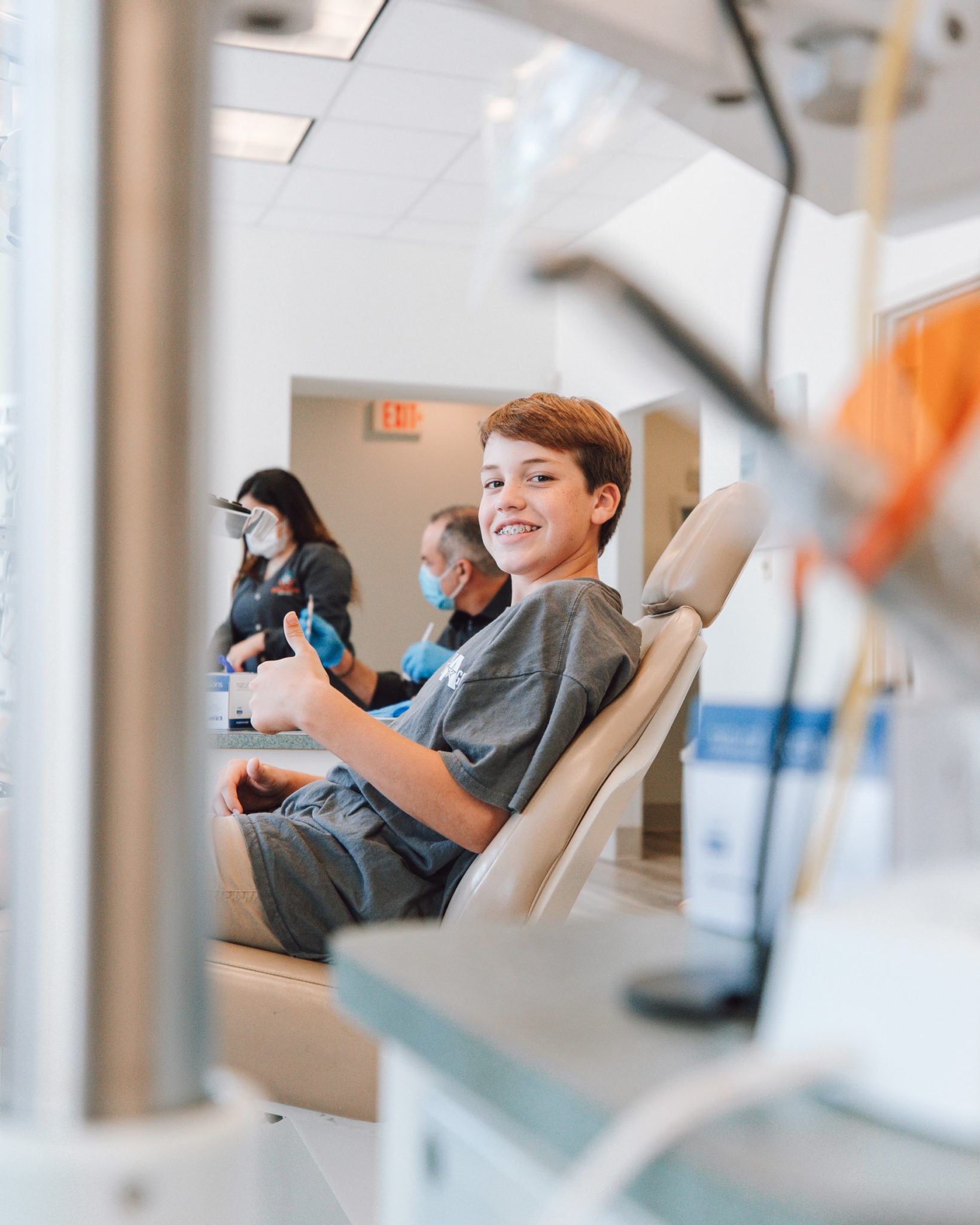 young boy smiling and giving a thumbs up in dental office