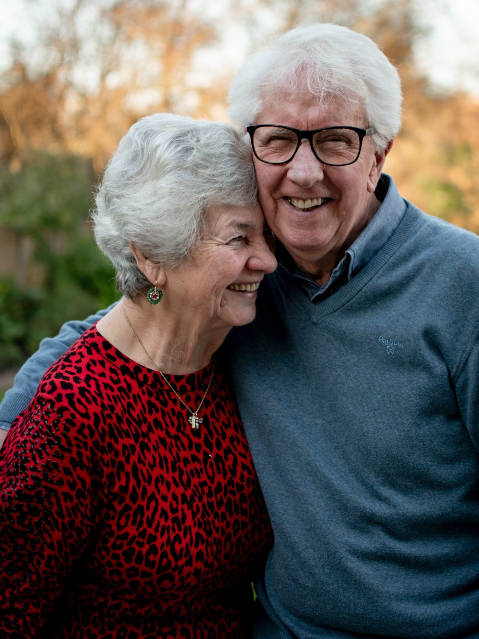 An elderly couple smiling and embracing