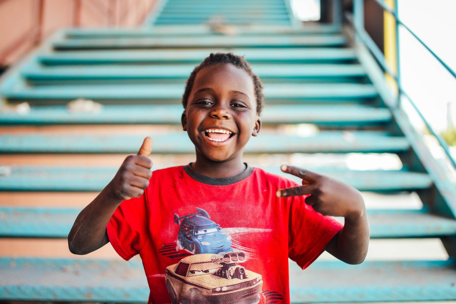 A smiling child near a stairway with a loose tooth