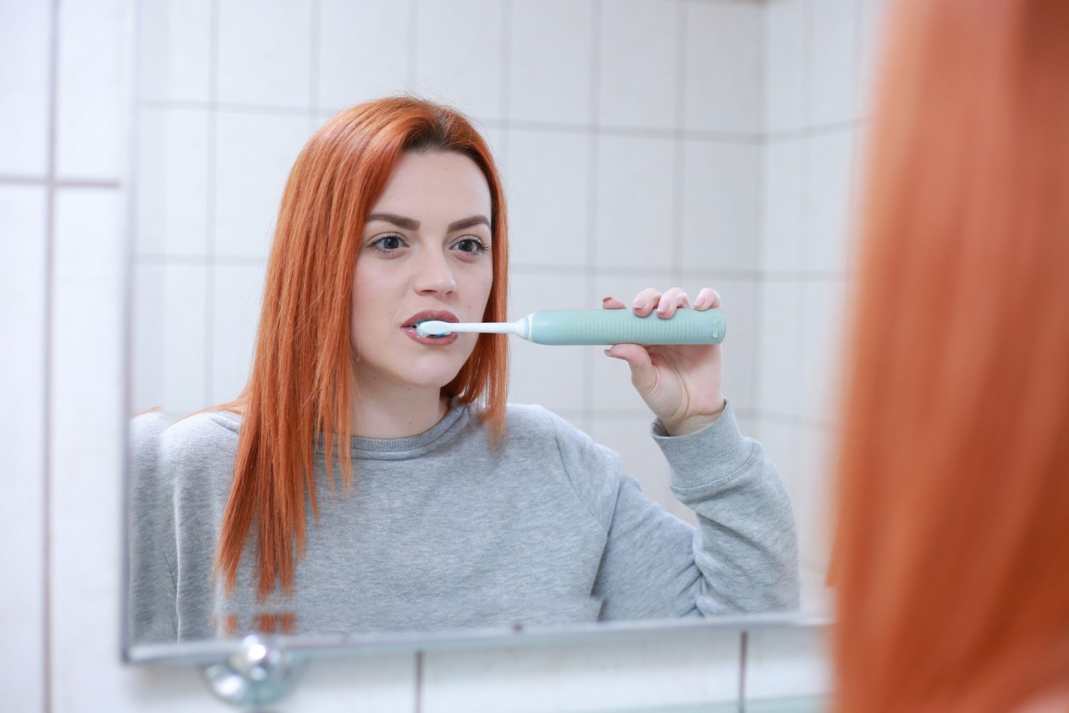 Woman brushing her teeth in the mirror