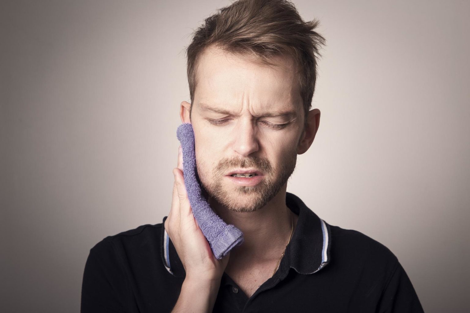 A man holding washcloth against cheek