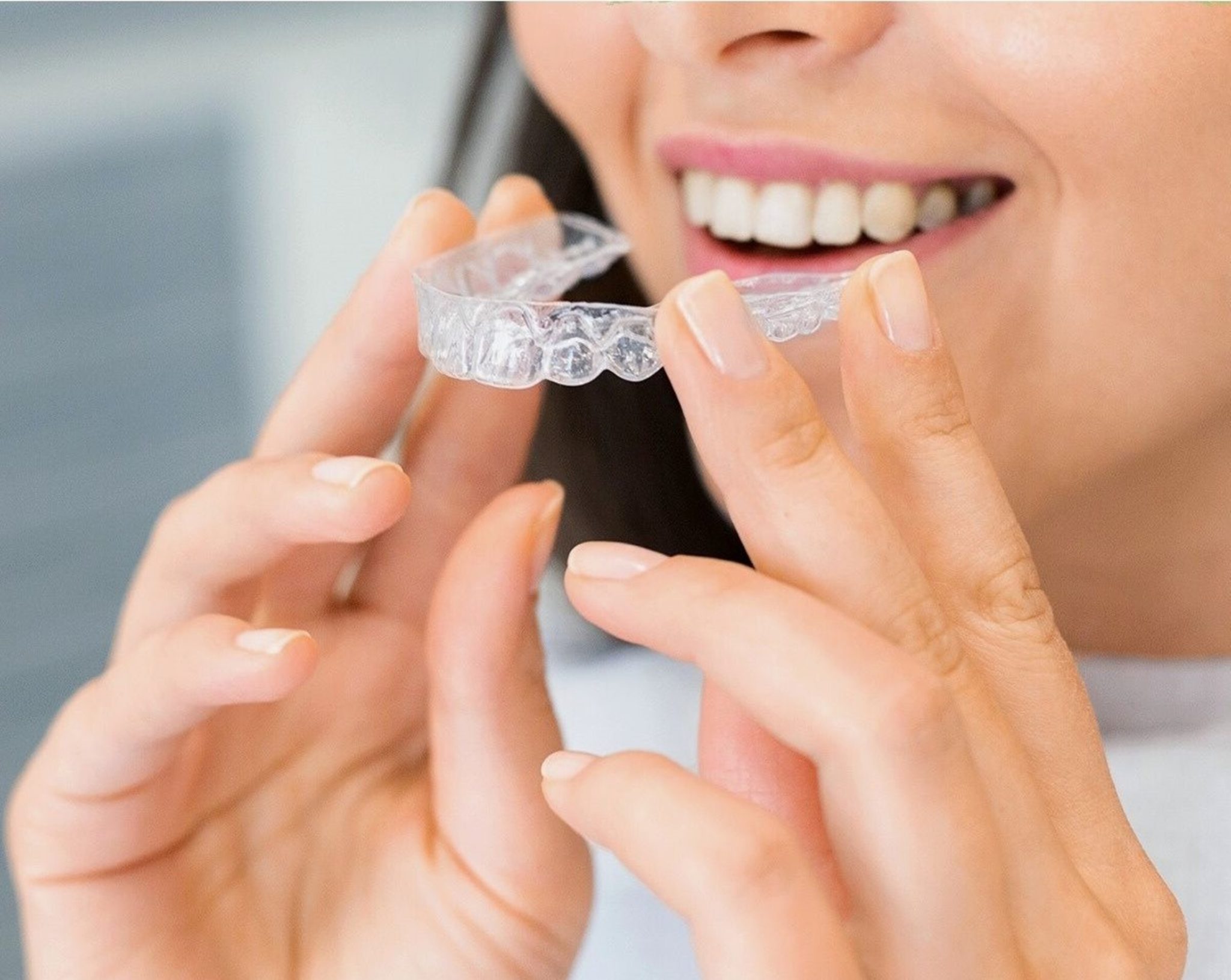 A woman holding a clear aligner