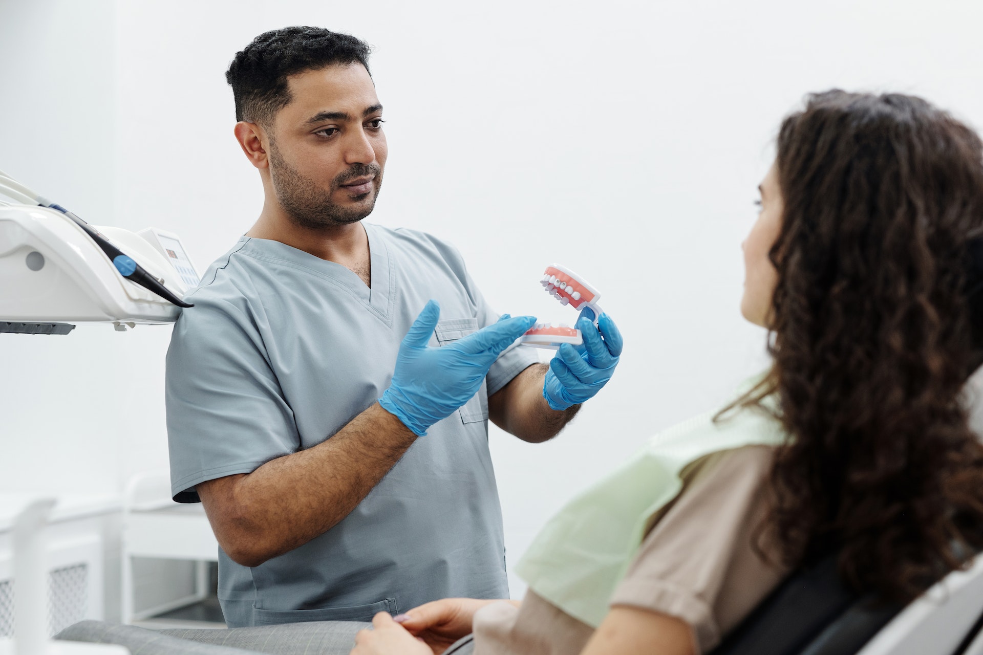 Dentist holding teeth model with patient