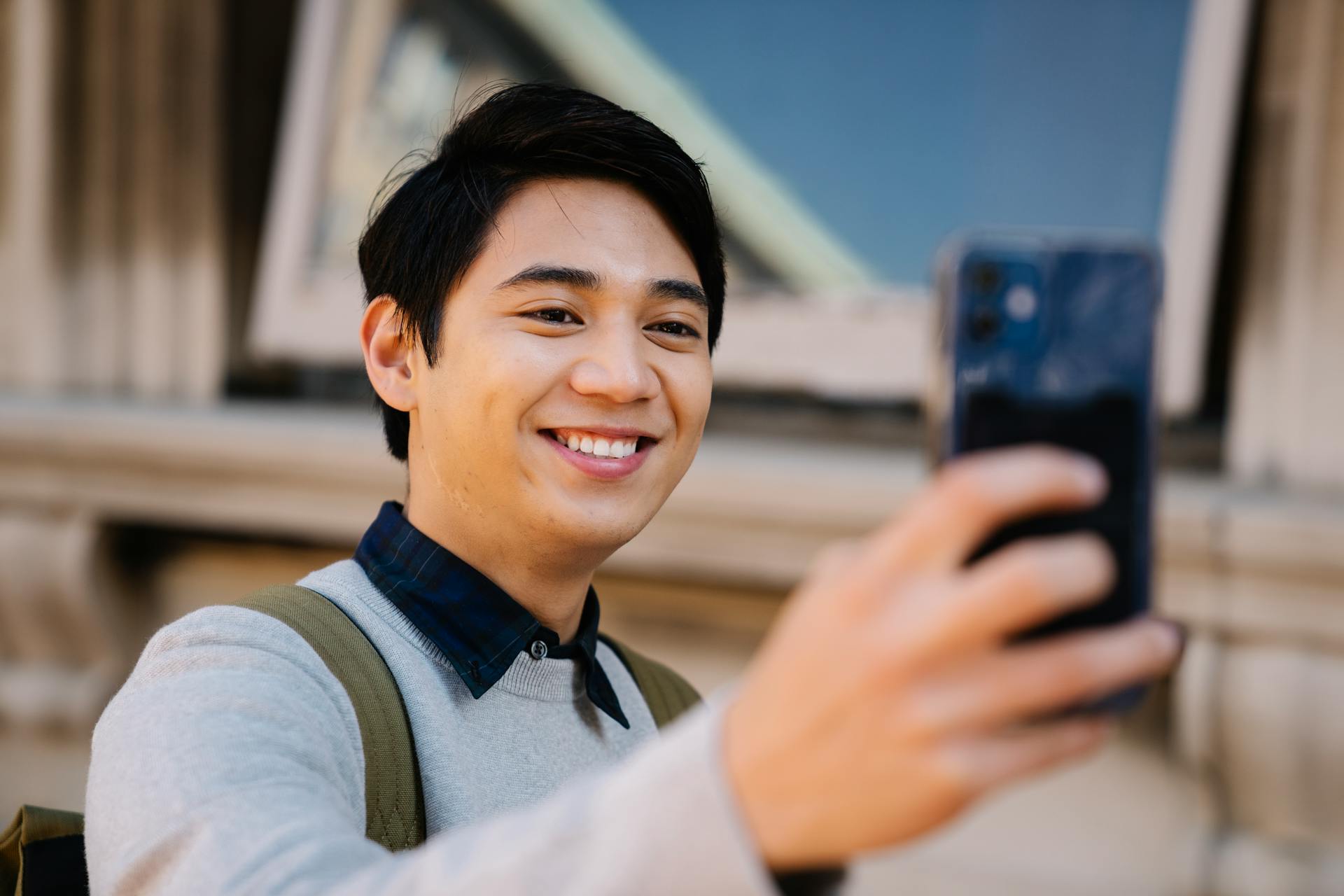 A man wearing a sweatshirt and taking a selfie