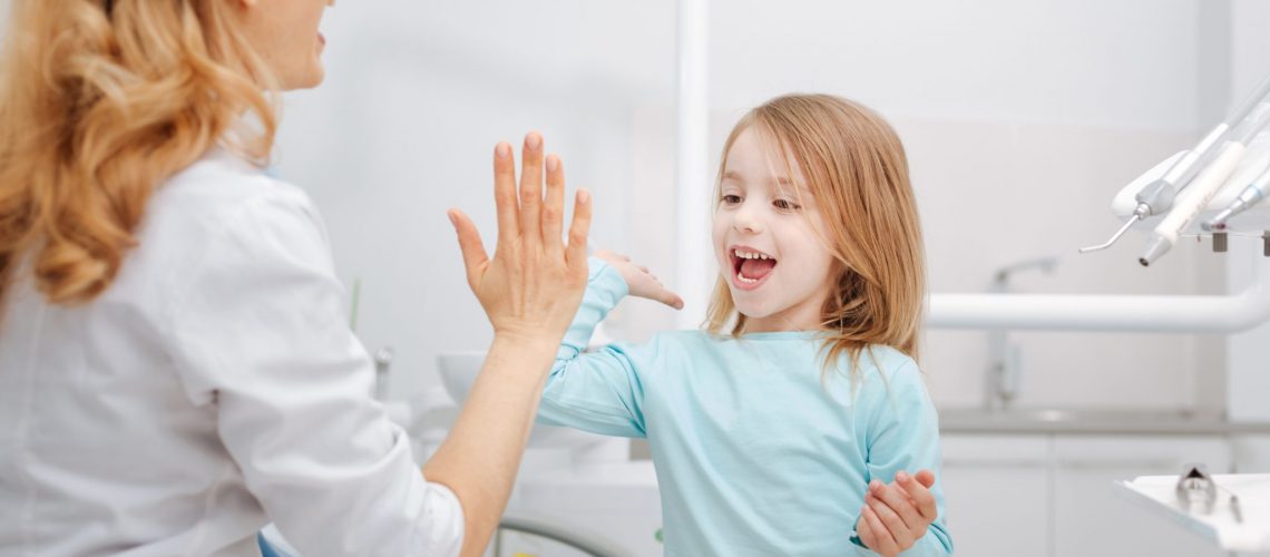 Creative Professional Dentist Giving Her Little Patient A High Five