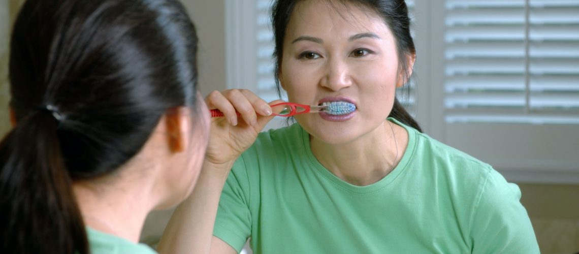 A woman brushing her teeth in the mirror