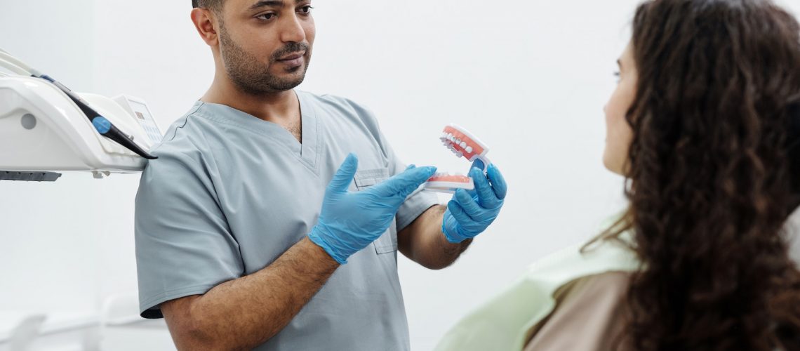 Dentist holding teeth model with patient