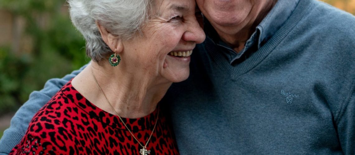 An elderly couple smiling and embracing