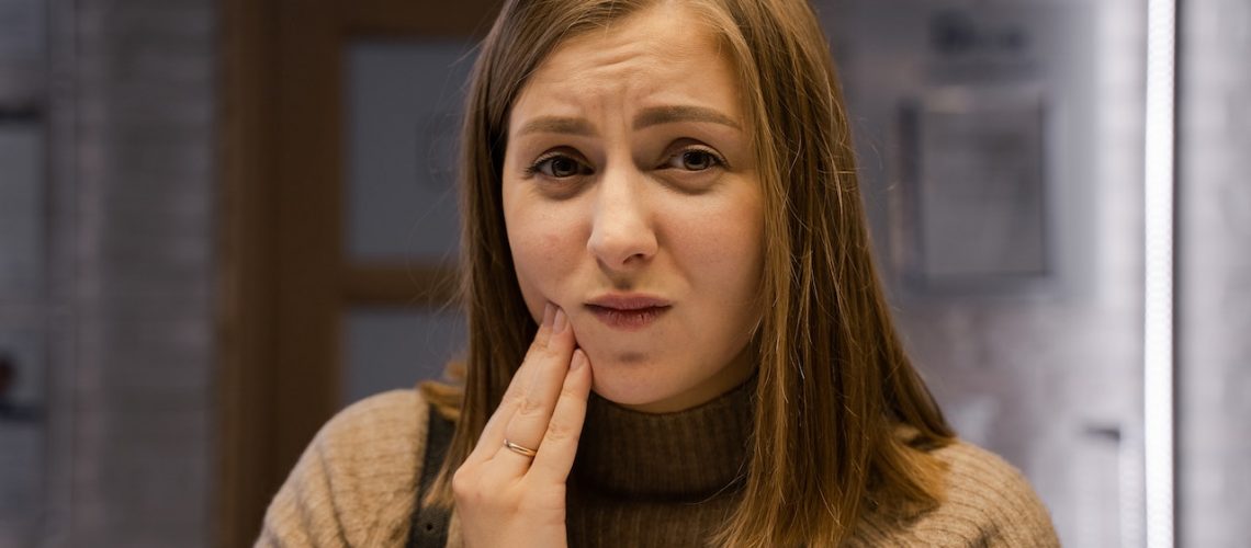 A woman with toothache holding her cheek