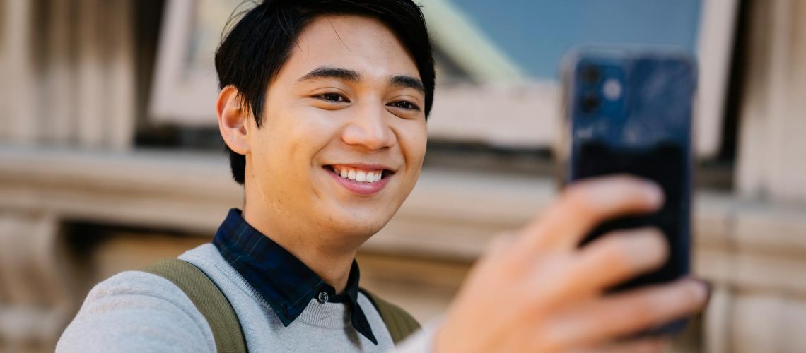 A man wearing a sweatshirt and taking a selfie