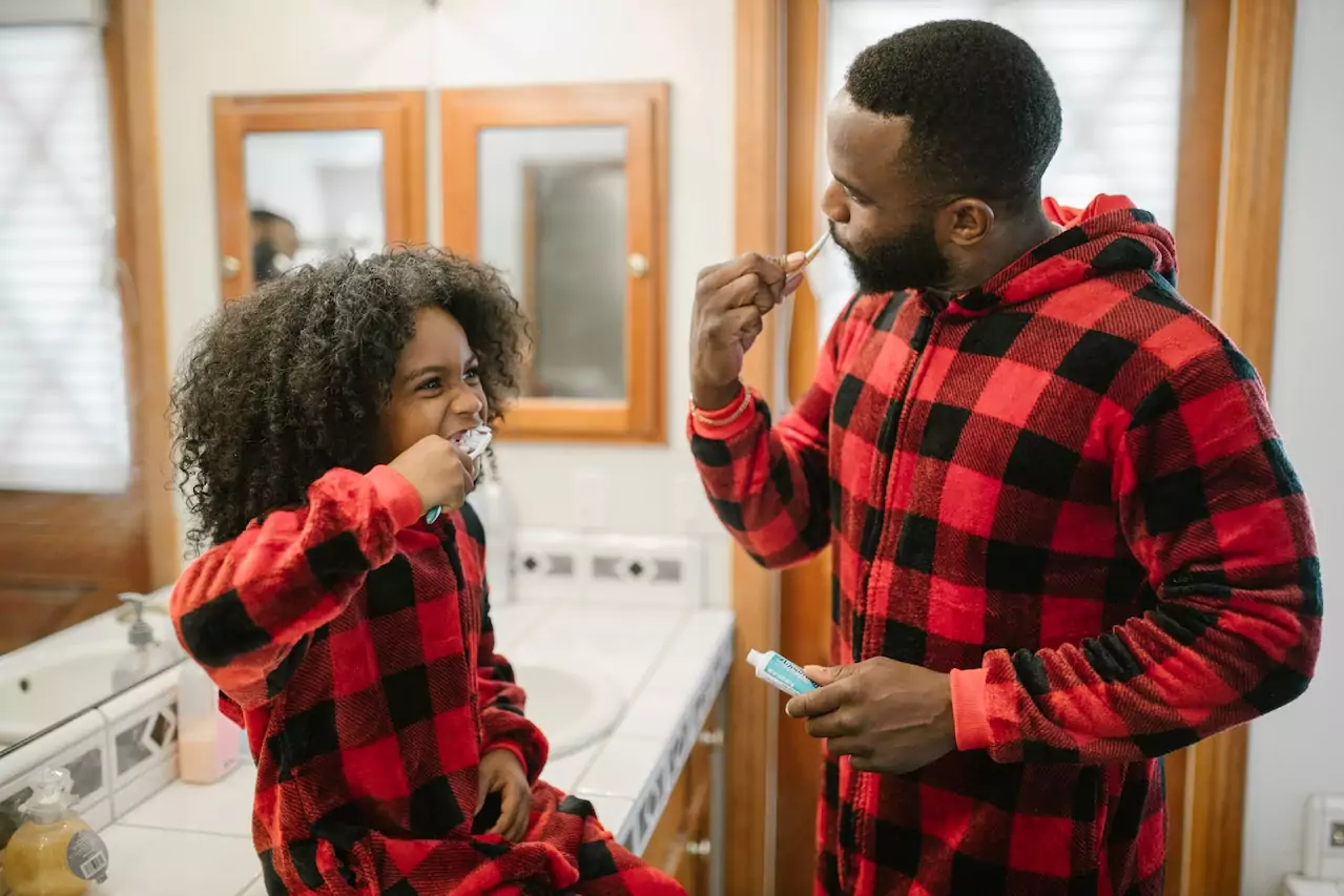 Daughter and father brushing their teeth together